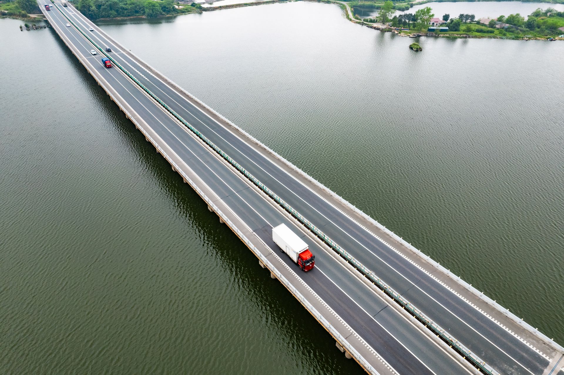 Camion traversant un long pont autoroutier au-dessus d’un lac